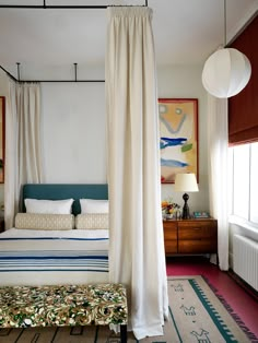 a bedroom with a canopy bed, rug and painting on the wall above it's headboard