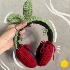 crocheted red slippers are being held up by a person's hand