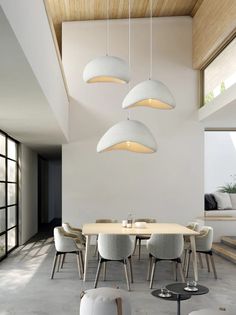 a dining room table with chairs and lights hanging from the ceiling