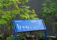 a blue sign in front of some bushes and trees