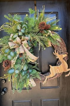 a christmas wreath on the front door with pine cones, evergreens and an ornament