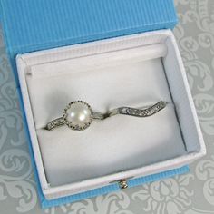 Timeless and classic, this vintage inspired pearl engagement ring and curved wedding band set are reminiscent of the Edwardian era when fine metalwork was designed with intricate details and delicate settings that were fashioned to resemble the patterns of fine lace. The vintage style Edwardian-inspired pearl ring is handcrafted from recycled sterling silver where a lightly oxidized floral band is set with a luminous 8-8.5mm cultured creamy white freshwater pearl in a filigree heart-crown settin 14kt Gold Jewelry, Floral Wedding Bands, Silver Pearl Ring, Filigree Heart, Pearl Engagement Ring, Traditional Engagement Rings, Edwardian Style, Curved Wedding Band, Local Jewelry