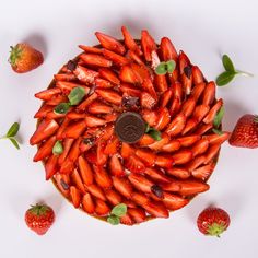 a cake with strawberries and mint leaves on the top is surrounded by chocolate chips