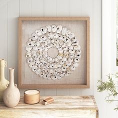 a wooden table topped with vases next to a framed art print on the wall