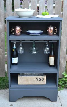 an old bookcase turned into a bar with wine glasses and plates on the shelf