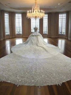 the wedding dress is on display in an empty room with chandelier and windows