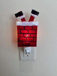 a light that is on the wall with santa's hat and legs attached to it