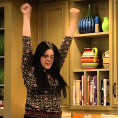 a woman standing in a kitchen holding her arms up