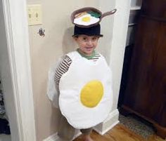 a young boy dressed up as an egg with a hat on his head standing in front of a door