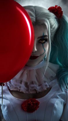 a woman with blue hair and makeup holding a red balloon