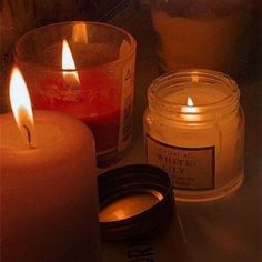 three candles sitting on top of a table next to a jar with some liquid in it