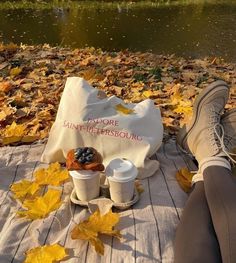 a person is sitting on the ground with their feet propped up next to two cups of coffee