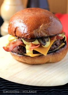 a cheeseburger with bacon and other toppings on a wooden board