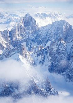 the mountains are covered in snow and clouds as seen from an airplane window, looking down on them