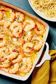 shrimp and pasta in a casserole dish next to a bowl of noodles on a table