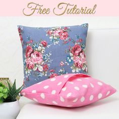 a pink pillow sitting on top of a white couch next to a potted plant