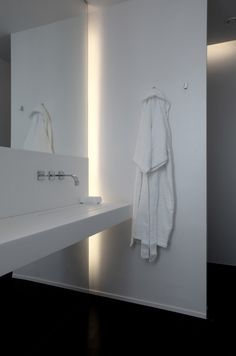 a white towel hanging on the wall next to a sink in a room with black floors