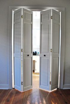 an open door leading to another room with wood floors and white walls, in the middle of a wooden floor