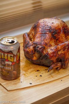 a whole chicken on a cutting board next to a can of root beer