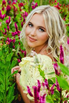 a beautiful blonde woman standing in a field of flowers