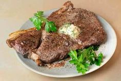 a steak with parsley on the side sits on a plate