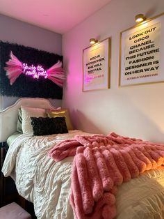 a bed with pink blankets and posters on the wall