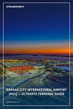 A twilight aerial view of Kansas City International Airport (MCI), showcasing its modern terminal building illuminated with vibrant red and blue lights, surrounded by snow-covered roads and runways. The sky transitions from deep blue to orange as the sun sets in the distance.