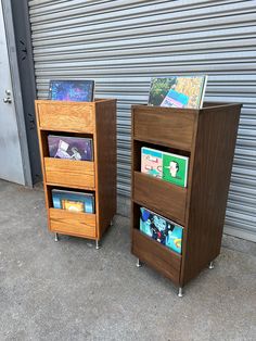 two wooden bookshelves sitting next to each other in front of a garage door