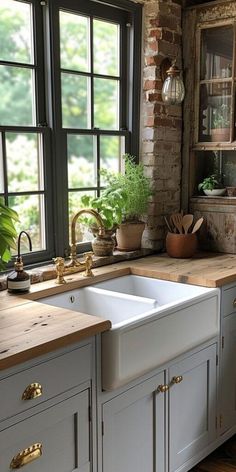 a kitchen with white cabinets and wooden counter tops next to a window filled with potted plants