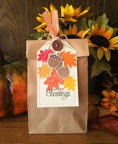 a paper bag with a tag on it sitting next to pumpkins and sunflowers