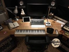 a desk with a keyboard, monitor and other musical equipment