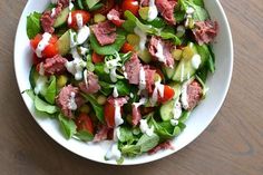 a white bowl filled with salad on top of a wooden table