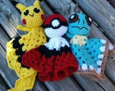 three crocheted stuffed animals sitting next to each other on a wooden surface,