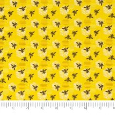 a yellow background with black and white flowers on it, which has a ruler in the foreground