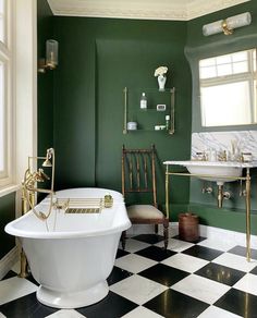 a bathroom with green walls and black and white checkered flooring, gold accents