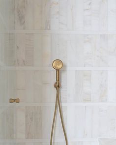 a gold shower head in a bathroom with white tiles on the wall and flooring