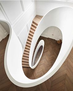 an aerial view of a spiral staircase in a house with wood floors and white walls