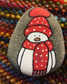 a painted rock with a penguin wearing a red hat and scarf