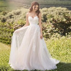 a woman in a wedding dress standing on the grass