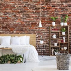 a bedroom with brick walls and white bedding, potted plants on the floor