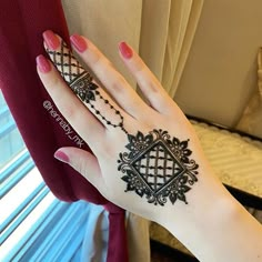 a woman's hand with a henna tattoo on her left wrist and the other arm