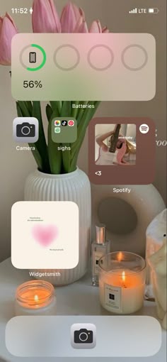 a cell phone with candles and flowers on the table in front of it is an image of someone's home screen