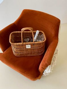 a wicker basket sitting on top of an orange chair with two glasses in it