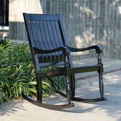 a black rocking chair sitting on top of a sidewalk