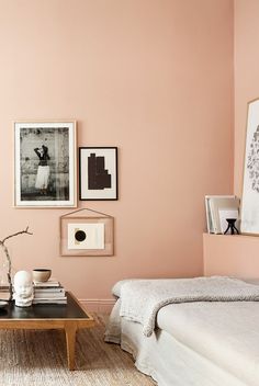 a living room with pink walls and pictures on the wall, coffee table and bed