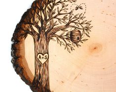 a wooden plate with an image of a tree and two birds on it, in the shape of a heart