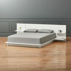 a bed sitting on top of a hard wood floor next to a white headboard