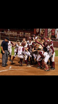 a group of people standing on top of a baseball field holding hands in the air