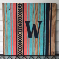 a wooden sign with the letter w painted on it's side hanging from a wall