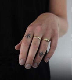 a person with two rings on their fingers and one has a flower tattoo on it